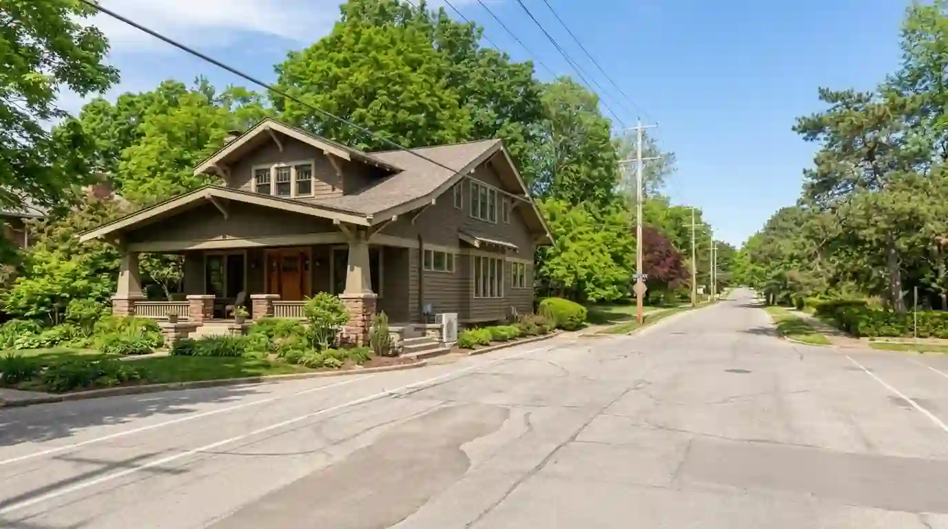 Craftsman bungalow with a deep front porch and wide eaves on Forest Park Boulevard in Fort Wayne, early summer, a slim ductless outdoor unit tucked beside the side steps.